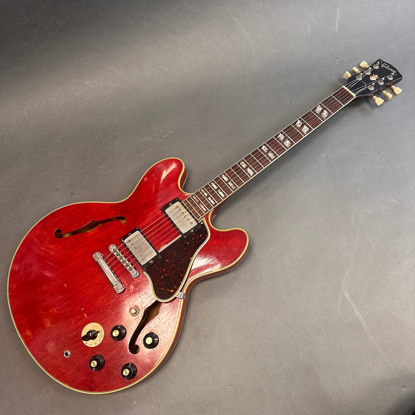 Vintage Gibson semi-hollowbody electric guitar in red finish with dual humbucker pickups and tortoiseshell pickguard on a grey background