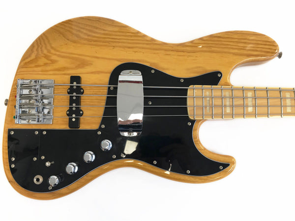 Natural finish electric bass guitar with black pickguard and chrome hardware on white background