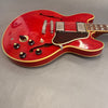 Red semi-hollow electric guitar with cream binding, chrome humbucker pickups, black control knobs, and tortoiseshell pickguard on grey background