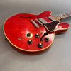 Red semi-hollow electric guitar with chrome bridge, black control knobs, cream binding, and tortoiseshell pickguard on gray background