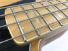 Close-up of maple fingerboard with rectangular inlays and metal frets on electric bass guitar strings