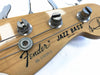 Close-up of Fender Jazz Bass headstock with tuning pegs, natural wood finish, and string winding detail, made in Japan model.