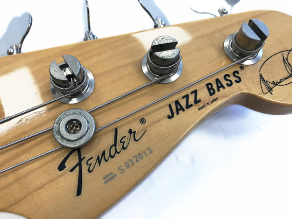 Close-up of Fender Jazz Bass headstock with tuning pegs, natural wood finish, and string winding detail, made in Japan model.