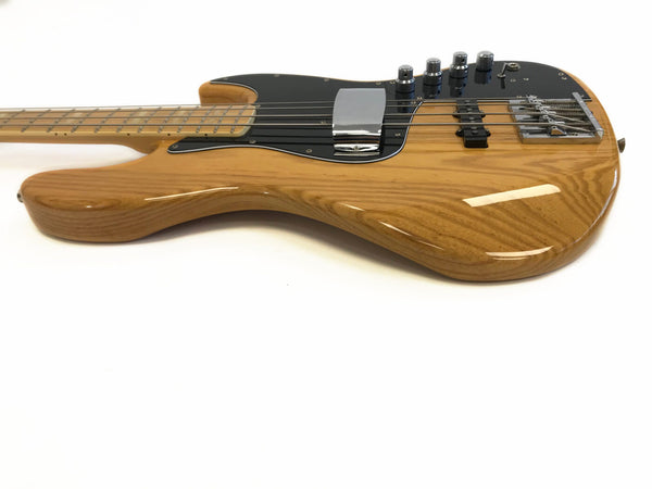 Natural wood finish electric bass guitar with black pickguard and chrome hardware on white background