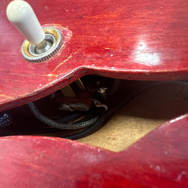 Close-up view of a red electric guitar body showing the pickup selector switch and internal wiring cavity.