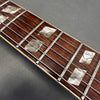 Close-up of guitar fretboard with diamond-shaped mother of pearl inlays and metal frets on a dark wooden neck