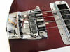Close-up of chrome bridge and saddle with strings on red electric bass guitar body