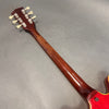Back of guitar neck and headstock with vintage tuning pegs on brown guitar neck against gray background
