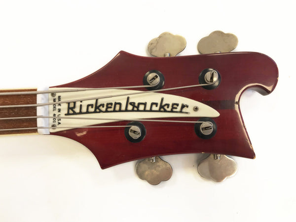 Close-up of red Rickenbacker Model 4001 bass guitar headstock with silver tuning pegs and white logo truss rod cover on white background