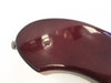 Close-up of deep red glossy electric guitar body with strap button and visible screw indentation on white background