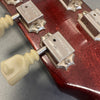 Close-up of vintage guitar tuning pegs with cream plastic keys on a worn red wooden guitar headstock featuring Maxcap brand metal tuners
