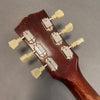 Close-up of the back of a vintage guitar headstock showing six metal tuning pegs with cream-colored tuning keys on a dark wood finish neck.