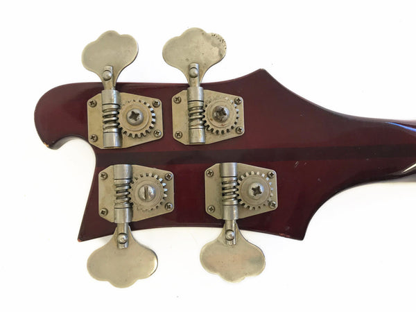 Close-up of vintage bass guitar headstock with four metal tuning pegs and dark reddish-brown finish against white background