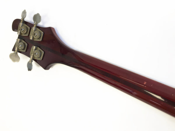 Back view of vintage bass guitar neck with dark wood finish and metal tuning pegs on white background