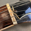 Close-up of worn guitar nut and steel strings on vintage acoustic guitar with black headstock and visible screw detail