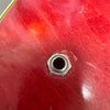 Close-up of red electric guitar body with metal input jack socket and visible wear marks.