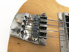 Close-up of vintage electric bass guitar chrome bridge and strings on natural wood finish body