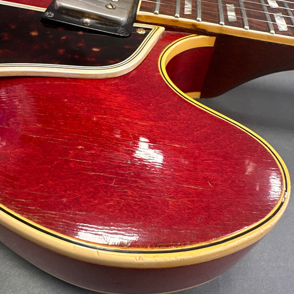 Close-up of vintage red electric guitar body with cream binding and visible wear detailing