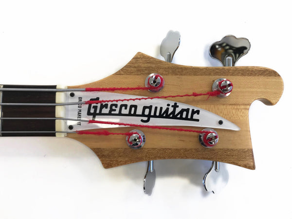 Greco bass guitar headstock with natural wood finish, black fretboard, chrome tuning pegs, and red-wrapped strings close-up on white background.