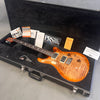 Paul Reed Smith PRS electric guitar with flame maple top in open black hard case, including tremolo arm, PRS logo sticker, manuals, and warranty cards