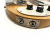 Close-up of vintage electric guitar instrument and amplifier input jacks with worn metal plate and black control knobs on natural wood body.