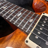 Close-up of electric guitar fretboard with bird inlays and humbucker pickup on a glossy wood finish guitar body at Coffee House Guitars