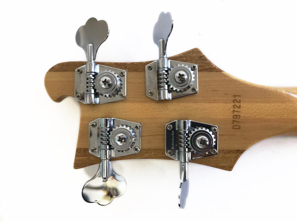 Close-up of bass guitar headstock with chrome tuning pegs and serial number D797221 on natural wood finish
