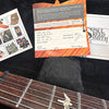 Close-up of Paul Reed Smith PRS guitar certificate of authenticity with model CU 24 and serial number 207054, set on black plush background next to guitar fretboard with bird inlay and several PRS promotional cards