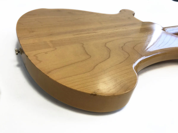 Close-up of natural finished wood back and side of electric guitar body showing wood grain and strap button with white background
