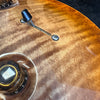 Close-up of amber sunburst electric guitar body showing tone control knob and three-way pickup selector switch on flamed maple top