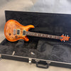PRS Custom 24 electric guitar with flame maple top in honey burst finish resting inside black plush-lined hard case
