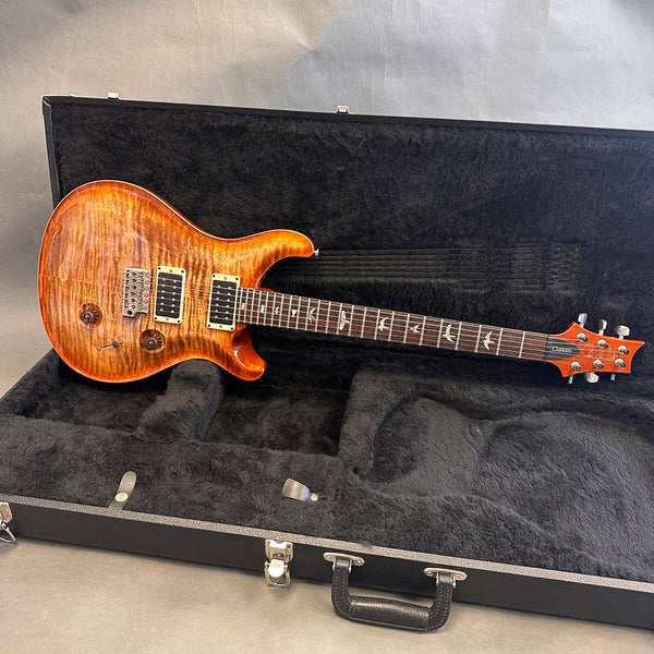 PRS Custom 24 electric guitar with flame maple top in honey burst finish resting inside black plush-lined hard case