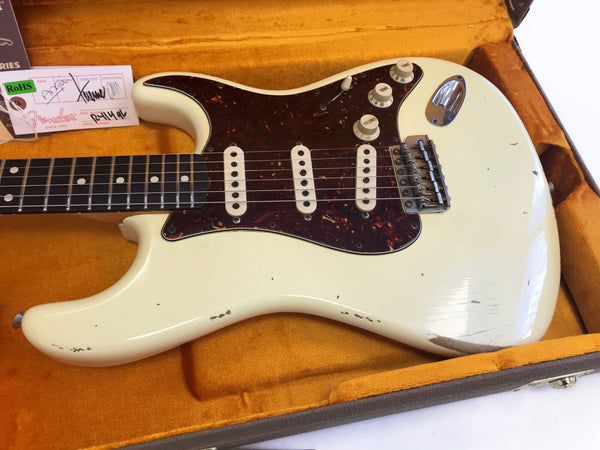 Vintage white Fender Stratocaster electric guitar with tortoiseshell pickguard and three single-coil pickups in orange plush-lined guitar case