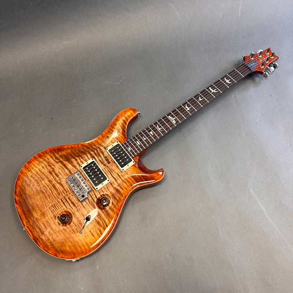 Electric guitar with flame maple top and bird inlays on fretboard on gray background