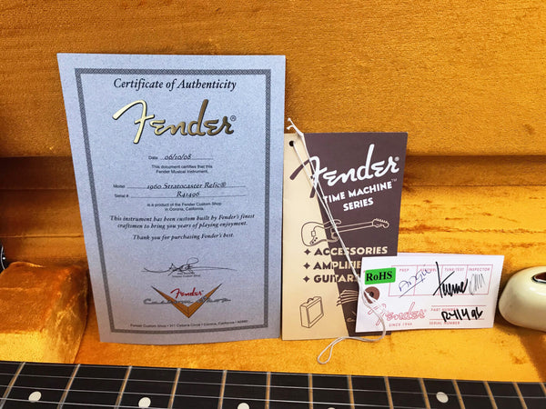 Fender 1960 Stratocaster Relic Certificate of Authenticity with Time Machine Series booklet and Fender guitar tag on orange guitar case background