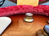 Close-up of volume control knob on amber sunburst electric guitar with plush red-lined case interior in background