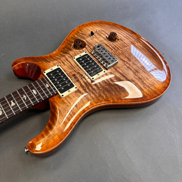 Electric guitar with flame maple top finish, dual humbucker pickups, and bird inlays on rosewood fretboard displayed on gray background.