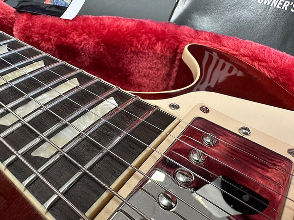 Close-up of electric guitar fretboard and chrome pickups with red and cream body in red plush-lined hard case