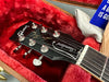 Close-up of Gibson Les Paul Standard guitar headstock with tuning pegs inside red plush-lined guitar case