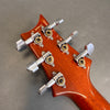 Close-up of mahogany guitar headstock with six silver tuning pegs and gear housings on gray background