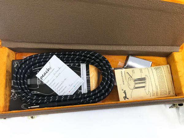 Vintage Fender guitar accessory case open with black and white instrument cable, Peach Guitars inspection card, Fender tremolo springs instruction sheet, and metal tremolo cover inside orange velvet interior
