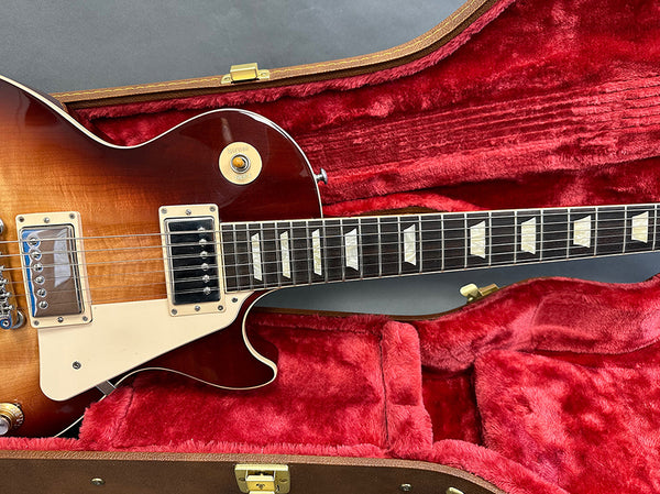 Electric guitar with sunburst finish in red plush lined guitar case, close-up of body and neck with trapezoid inlays and dual humbucker pickups