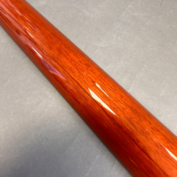 Close-up of glossy polished wooden guitar neck showing fine wood grain and orange-brown finish on gray background