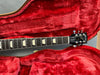Close-up of Gibson Les Paul Standard electric guitar neck and headstock inside red plush-lined guitar case