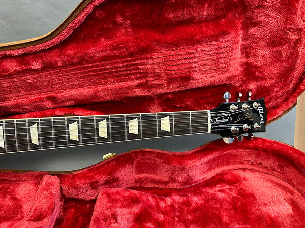 Close-up of Gibson Les Paul Standard electric guitar neck and headstock inside red plush-lined guitar case