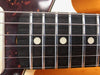 Close-up of bass guitar fretboard with metal frets, dot inlays, and metal strings on dark wood fingerboard