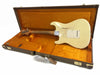 Vintage Fender Stratocaster electric guitar in aged white finish with visible wear, shown from back inside an orange plush lined vintage brown hard case with Fender logo