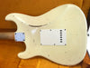 Vintage worn cream electric guitar back with neck plate and tremolo cavity cover on orange fabric background