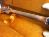 Close-up of vintage maple guitar neck with tuning pegs, resting in orange plush lined guitar case interior at Coffee House Guitars.
