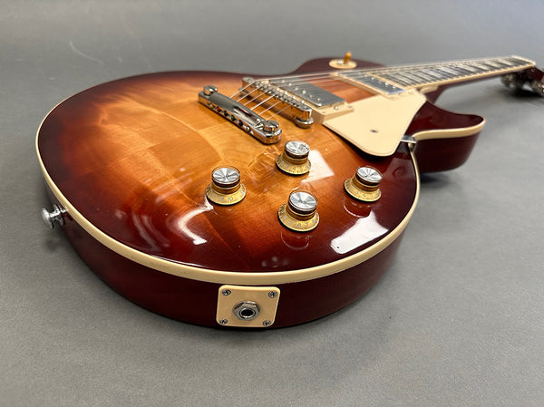 Close-up of a sunburst electric guitar body with cream binding, chrome bridge, and four control knobs on a gray surface, product image for Coffee House Guitars.